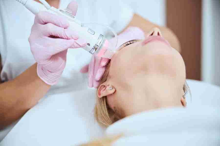 Cosmetologist treating her patient with a microneedle beauty machine Cropped photo of a skilled dermatologist carrying out a skin rejuvenation procedure on her client