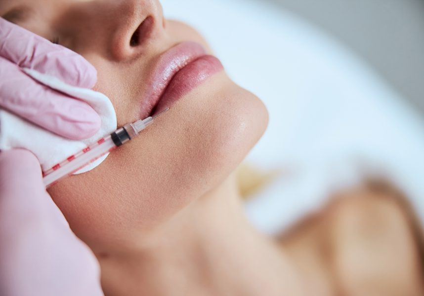 Certified doctor performing the lip augmentation procedure Close up of a young female patient undergoing a non-invasive cosmetic treatment in a beauty clinic